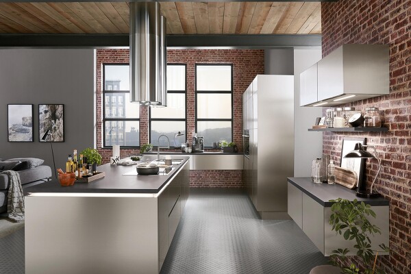 Durch die Ziegelwand kommt die INOX 216-Küche, im Look der Nachbildung von gebürstetem Stahl, ideal zur Geltung. Perfekt um so den den kühlen, klaren Industrial-Style in Ihrem Zuhause zu kreieren.